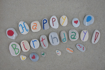 Happy Birthday on carved stone letters over the sand 