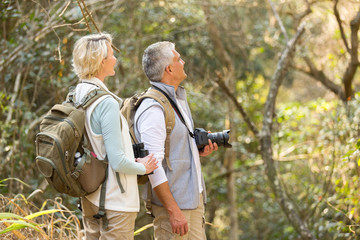 middle aged couple bird watching in forest