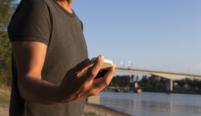 A man holding a phone in the backgrund a bridge