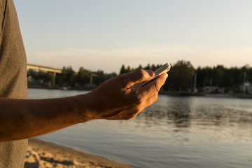A phone in a mans hand in front of a river