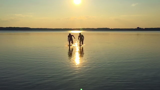 SLOW MOTION: Two men running along the water