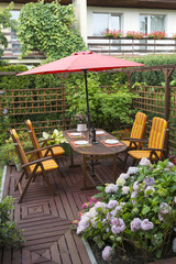 Wooden furniture with umbrella in backyard patio.