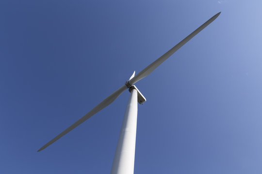 A diagonal capture of a wind turbine on a almost clear blue sky