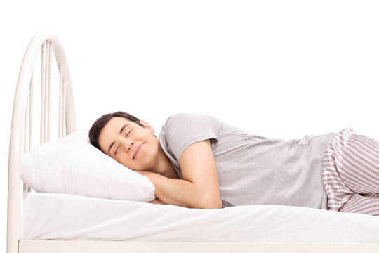 Happy young man sleeping in a bed