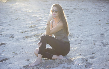 Fototapeta na wymiar Girl sitting in sand, with eyeglasses posing for camera.