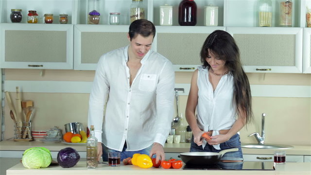 The girl chopped carrots, a guy gives her a tomato