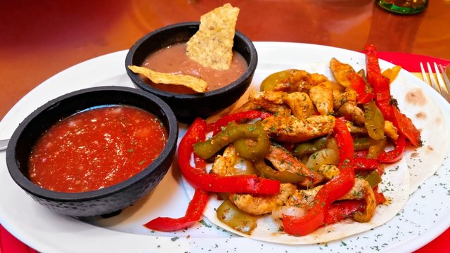 Chicken and bell pepper fajitas on tortilla bread with salsa and beans