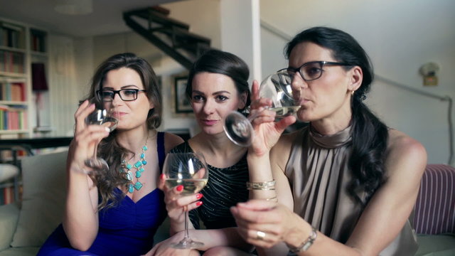 Girlfriends sitting in the apartment and drinking wine, steadycam shot
