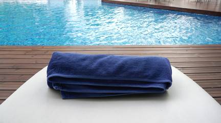 navy blue towel rolled on the white beach bed