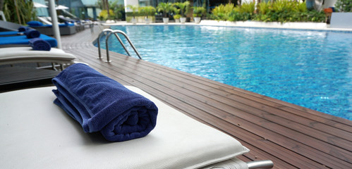 navy blue towel rolled on the white beach bed