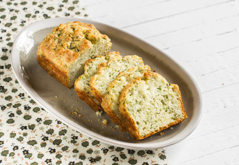 cake with cheese and herbs on an oval plate on a light wooden background