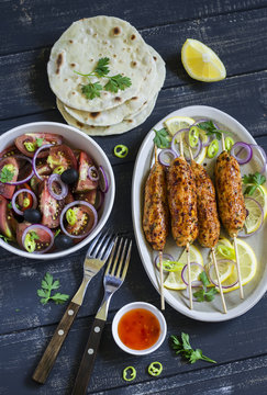 chicken kebab, salad with tomatoes, onions and olives, homemade tortilla is a healthy and delicious meal, on a dark wooden background
