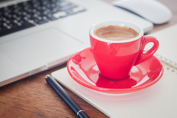 Red coffee cup with notepad and laptop