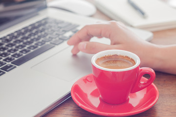 Red coffee cup with notepad and laptop