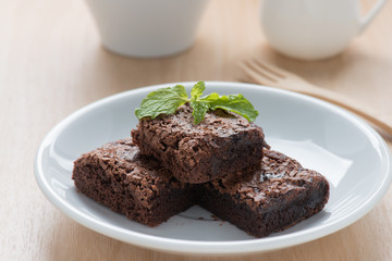 Pile of brownies on white dish.