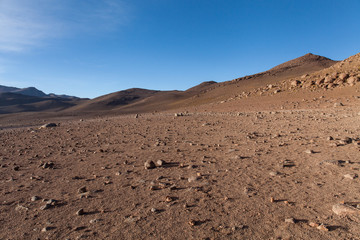 Deserto del Dali. Montagne e rocce in una distesa di sabbia. Cielo blu e montagne sullo sfondo