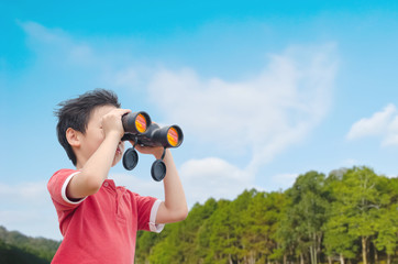 Young Asian boy using binoculars in forest