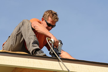 Building contractor putting the asphalt roofing on a large commercial apartment building.