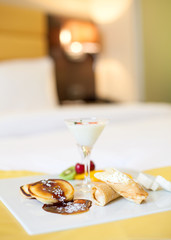 Fruit and chocolate deserts in hotel on a bed