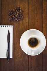 Cup of coffee and notepad with pen
