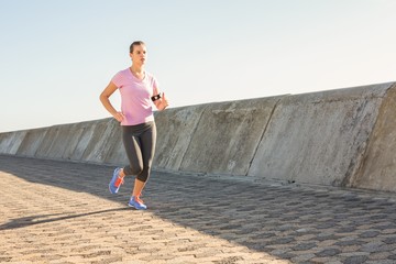 Sporty blonde jogging at promenade