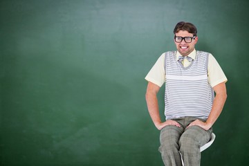 Composite image of geeky hipster sitting on stool