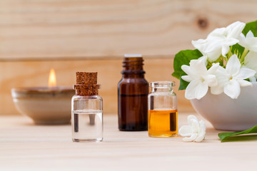 Aroma oil bottles arranged with jasmine flowers on wooden backgr