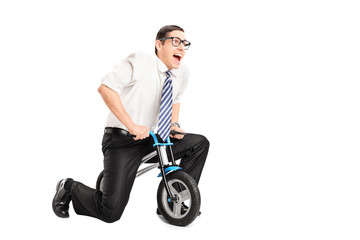 Fototapeta na wymiar Silly young businessman riding a small bike