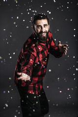 Portrait of a happy young man with beard, dancing between confet