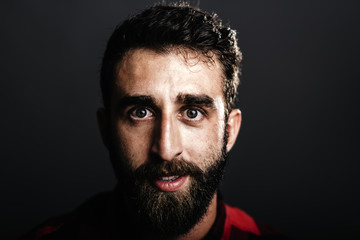 Portrait of a happy young man with beard smiling against gray ba