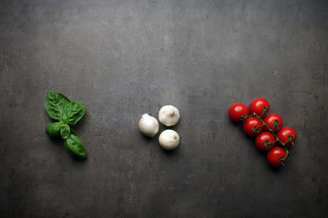 Italian ingredients - basil, onion and tomatoes on grey kitchen table