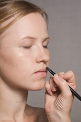 Beautiful woman having lipstick applied by make-up artist