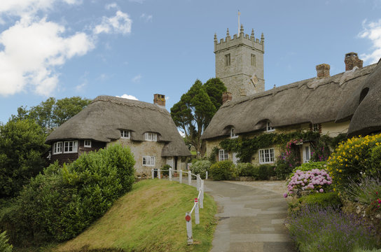 The pretty thatched cottages of Church Hill, with All Saints church in the background.l