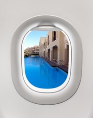 Looking out the window of a plane to the hotel swimming pool