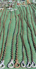 Rusty old tow chains lined up on a green tarpaulin at a car boot sale.