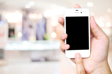 Hand holding smart phone over blur store background