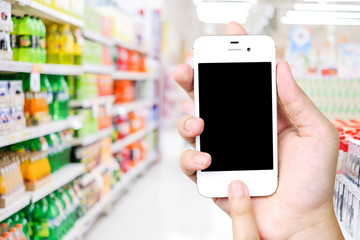Hand holding smart phone over blur supermarket background