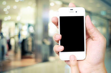 Hand holding smart phone over blur store background, business an