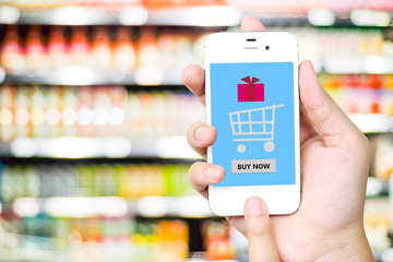 Fototapeta na wymiar Hand holding smart phone over blur supermarket background