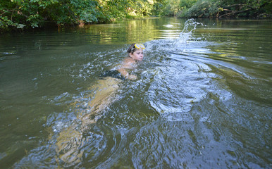 Boy teenager swims in  river in summer
