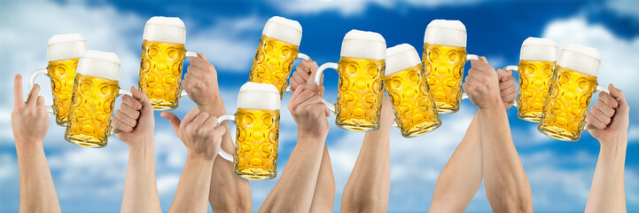Hands with beer mugs on blue cloudy sky