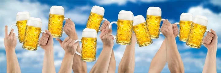 Foto auf Leinwand Hands with beer mugs on blue cloudy sky © stockphoto-graf