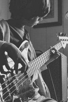 Boy feeling the music as he practices his bass guitar