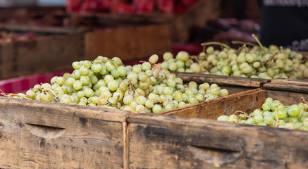 Old wooden crates filled with green table grapes at an October farmer's market.