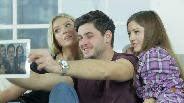 Guy and two girls make selfieie with a tablet