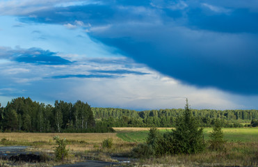 layers of storm clouds on the background fields and forests