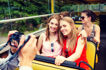 smiling friends with camera traveling by tour bus