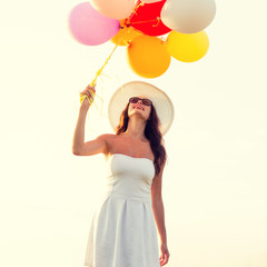 smiling young woman in sunglasses with balloons