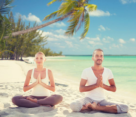 Fototapeta na wymiar smiling couple meditating on tropical beach