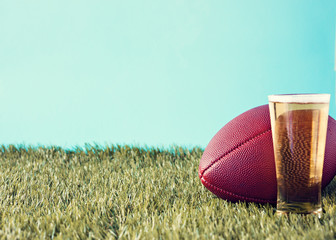Vintage football over grass and beer glass